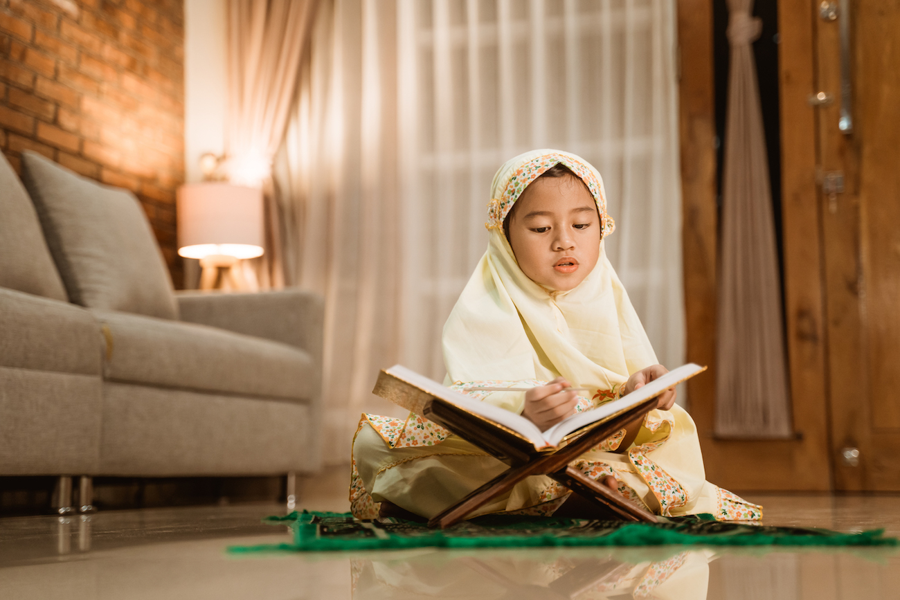 little girl reading quran wearing muslim hijab