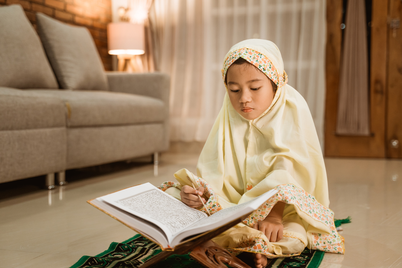 little girl reading quran wearing muslim hijab